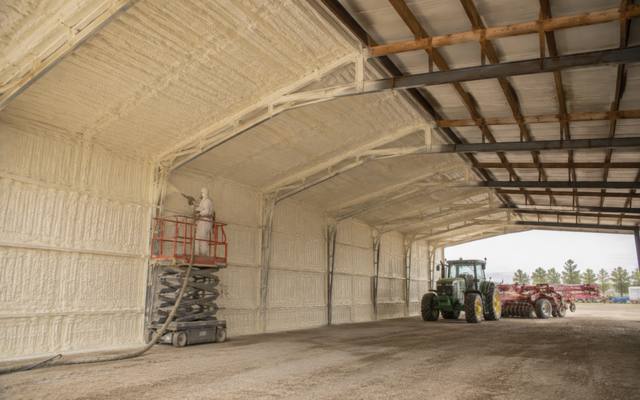 Machine storage barn being sprayed with foam from a scissor lift