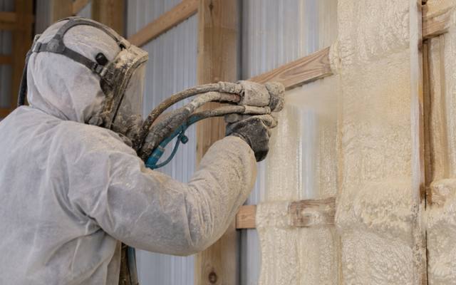 Closed-cell spray foam being applied between steel wall girts