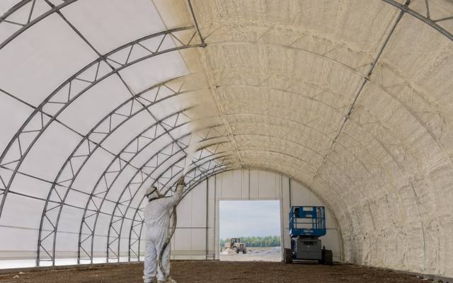 Fabric-covered arch growing building sprayed along the roof line